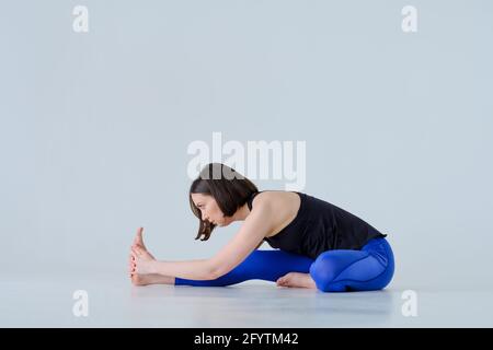 Fit donna in abbigliamento sportivo praticando yoga cancello posa a casa. Foto Stock