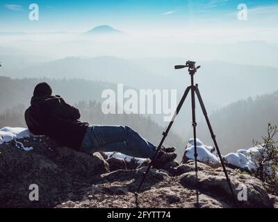 Il fotografo si adagiato sulla neve sparando un pittoresco paesaggio invernale. Composizione dell'inquadratura dell'artista con la fotocamera in mano Foto Stock