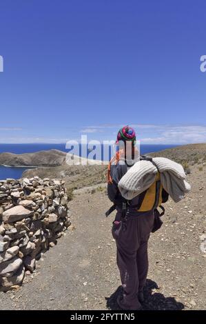 Un turista vicino all'Isla del Sol con le montagne delle Ande Sul lato boliviano del lago Titicaca Foto Stock