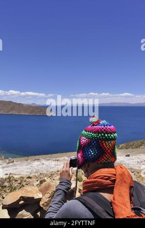 Un turista vicino all'Isla del Sol con le montagne delle Ande Sul lato boliviano del lago Titicaca Foto Stock