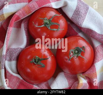 Tre pomodori biologici ecologici freschi con biancheria da cucina stoffa vista dall'alto. Foto Stock