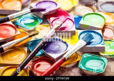 Set di coloratissime vernici ad acquerello e pennelli per la verniciatura di closeup. Messa a fuoco selettiva. Foto Stock