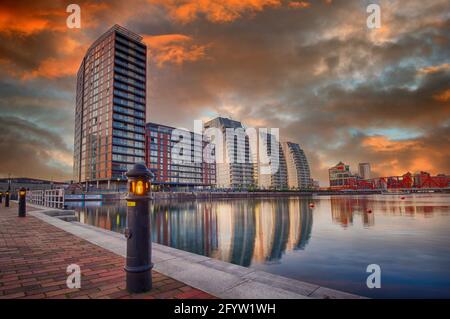 Il sole tramonta sugli edifici NV e su uno dei moli di Salford Quays, Salford, Lancashire, Regno Unito Foto Stock