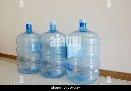 Le bottiglie vuote in plastica usate dello scambiatore di calore dell'acqua si allineano sul pavimento Foto Stock