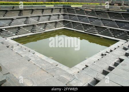 Un laghetto storico con gradini di pietra vestita a Hampi (Vijayanagar), Karnataka, India, Asia Foto Stock