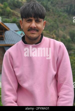 Ritratto di un giovane ragazzo di buon aspetto con felpa di colore rosa, UN bel giovane indiano del nord in piedi all'aperto con la vista della macchina fotografica Foto Stock