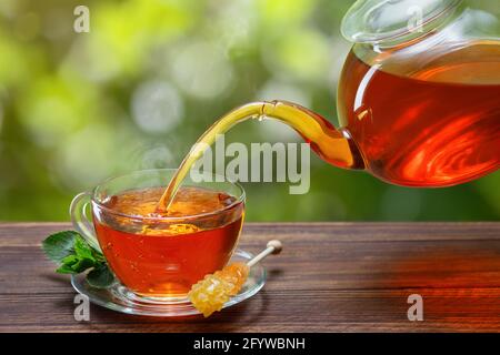 tè con la menta che si versa dalla teiera in tazza Foto Stock