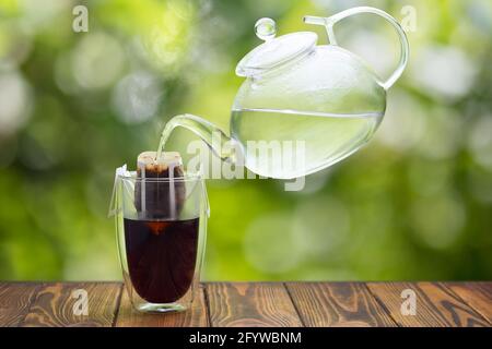 versare il caffè a mano in vetro su un tavolo di legno Foto Stock