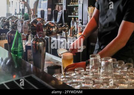 (210530) -- BRUXELLES, 30 maggio 2021 (Xinhua) -- Luke Nolan usa un raschiatore per strisciare la schiuma nella barra 'Funky Monkey', a Bruxelles, Belgio, 28 maggio 2021. Per il bar manager Luke Nolan, la decisione del governo belga di consentire al settore alberghiero di riaprire terrazze all'aperto dall'8 maggio è arrivata non troppo presto. Prima di allora, Luke e i suoi colleghi sono sopravvissuti mesi di dura gestione del bar a causa della pandemia COVID-19, fornendo pasti da asporto la sera. "E' stato un grande sollievo per tutti ed eccellente per noi essere di nuovo al lavoro ed eccellente per la nostra salute mentale. Per pisello Foto Stock