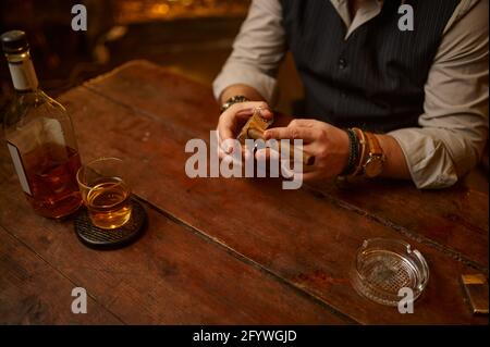 Uomo con ghigliottina taglia un sigaro, fumo di tabacco Foto Stock