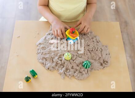 bambino piccolo che gioca con sabbia cinetica e giocattoli al tavolo Foto Stock