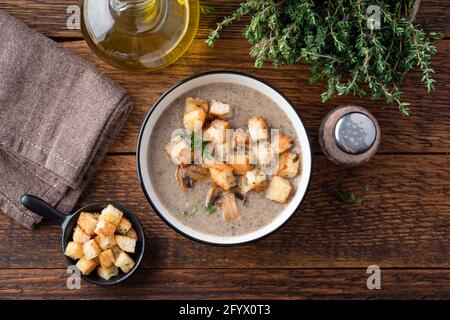 Crema di zuppa di funghi con crostini, timo e olio d'oliva su un tavolo di legno sfondo, vista dall'alto Foto Stock