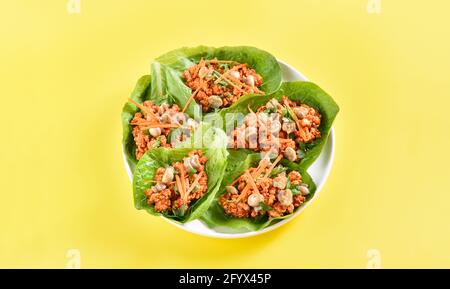 Tazze di lattuga di carne tritata in stile asiatico su sfondo giallo con spazio libero per il testo. Vista ravvicinata Foto Stock