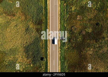 Vista aerea del camion sulla strada attraverso la campagna nel soleggiato pomeriggio estivo Foto Stock