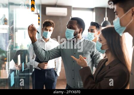 Uomini d'affari che hanno una riunione usando note post-it appiccicose sulla parete di vetro Foto Stock