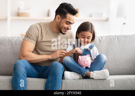 Bambina e papà risparmiando soldi in banca piggy Foto Stock