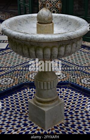 Fontana in marmo ornato, circondata da mosaici geometrici, in un cortile del Palazzo Bahia del XIX secolo, Marrakech, Marocco, Nord Africa. Foto Stock