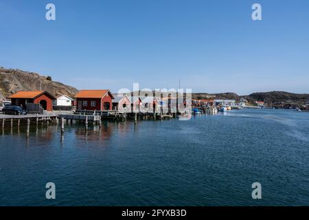 17 aprile 2021 - Hamburgsund, Svezia: Un pittoresco villaggio di pescatori sulla costa occidentale svedese. Tradizionali capanne di mare rosso e un cielo blu sullo sfondo Foto Stock