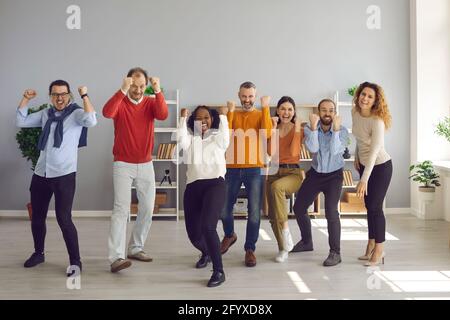 Team di felici ed eccitati diversi uomini d'affari che celebrano il successo e. divertirsi Foto Stock