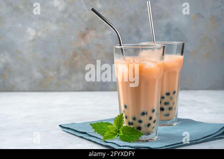 Due bicchieri di tè tapioca su sfondo grigio con spazio per la copia. Tè fatto in casa con bolle di latte con perle di tapioca. Bevanda rinfrescante taiwanese. Foto Stock