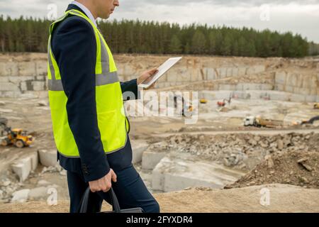 Architetto contemporaneo in uniforme che utilizza il tablet mentre si sposta lungo la costruzione sito Foto Stock