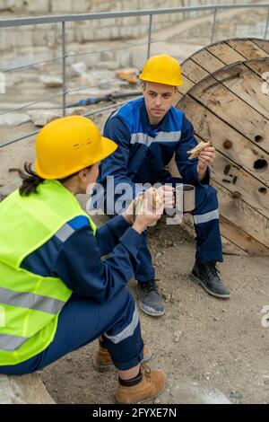 Due costruttori che chiacchierano e pranzavano a pausa Foto Stock