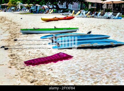 Sure boards, kayak e sedie a sdraio vuote al mattino presto in un resort sulla spiaggia dei caraibi Foto Stock