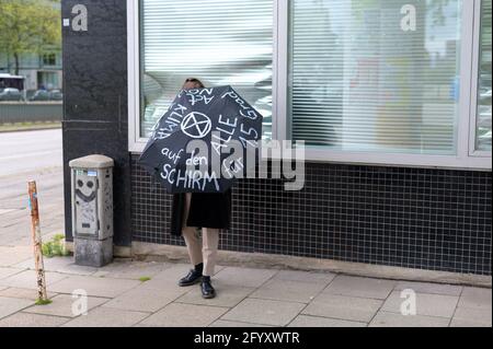 Amburgo, Germania. 27 maggio 2021. Un attivista si trova davanti ad un edificio d'ufficio con un ombrello descritto. Diversi gruppi locali di ribellione per l'estinzione hanno chiesto una migliore copertura della crisi climatica in caso di azioni decentrate di fronte alle case dei media sotto lo slogan "crisi climatica sulle prime pagine". Credit: Jonas Walzberg/dpa/Alamy Live News Foto Stock