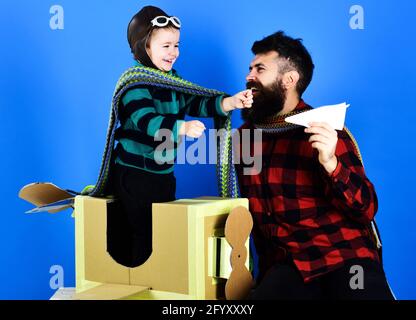 Concetto di genitorialità. Felice figlio che gioca con il padre. Papà e bambino gioca con aereo di cartone. Divertimento per tutta la famiglia. Foto Stock