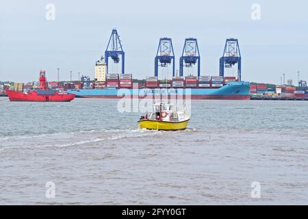 Harwich Harbour Ferry cita il suo commercio da Harwich a Felixstowe con una nave leggera e la Volga Maersk sullo sfondo. Foto Stock