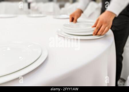 Il cameriere del ristorante serve il tavolo da pranzo. Primo piano impostazione ristorante. Messa a fuoco, sfocatura della foto. Foto Stock