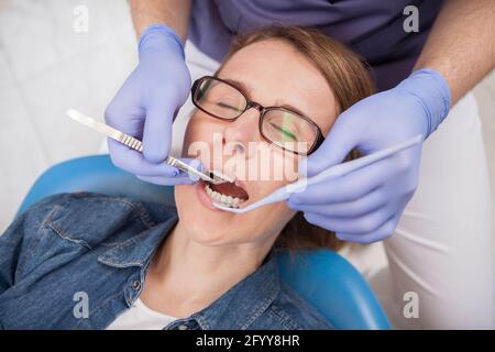 Vista dall'alto in primo piano di una donna matura che diventa dentale checkup da dentista professionista Foto Stock