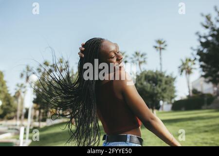 Allegra ragazza afroamericana amichevole con capelli ricci mostrando gesto di saluto in camera luminosa Foto Stock