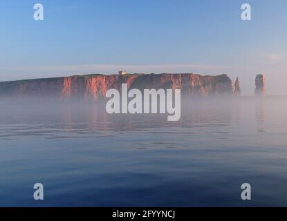 Vista dal Mare di Foggy alle scogliere Rusty e. Il famoso Sea Stack Lange Anna del Mare del Nord Isola Helgoland in UN giorno estivo soleggiato con UN chiaro B Foto Stock
