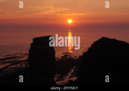 Tramonto sul Mare del Nord Isola Helgoland su UN sole Giorno d'estate con la silhouette del famoso Sea Stack Lange Anna in primo piano Foto Stock