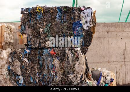 Scatole di plastica di verdure e frutta sono pressate in una fabbrica di rifiuti. I rifiuti di plastica vengono distribuiti per tipo e compressi a cubetti prima del transpo Foto Stock