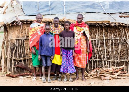 Famiglia Massai che guarda in macchina fotografica di fronte alla capanna Foto Stock