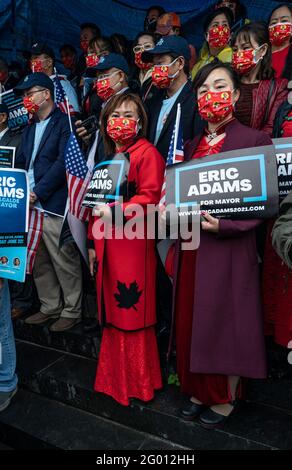 Sostenitori in abiti tradizionali partecipare al rally campagna a sostegno di Eric Adams offerta per il sindaco di NYC organizzato dalla comunità asiatica americana di fronte alla biblioteca pubblica Queens di Flushing. Adams è stato raggiunto dal rappresentante degli Stati Uniti Tom Souzzi, dal presidente del Queens Borough Donovan Richards e dal membro del consiglio comunale Peter Koo. Il Rally si tenne sotto la pioggia battente e molti sostenitori asiatici dicevano che era per fortuna, dato che la tradizione cinese amava l'acqua. Il Rally si è tenuto nel fine settimana del Memorial Day e i tifosi stavano tenendo bandiere nazionali americane. Foto Stock