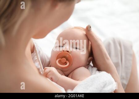 Madre felice e bambino carino sul letto a casa, primo piano Foto Stock