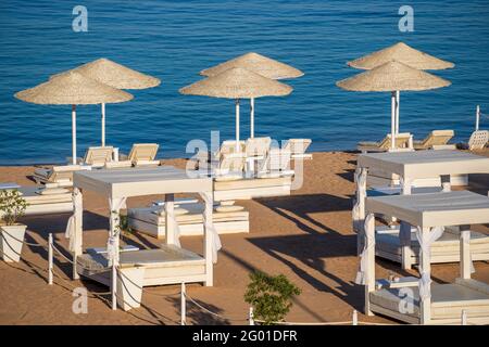 Spiaggia di sabbia di lusso con sedie a sdraio e ombrelloni bianchi in resort tropicale sulla costa del Mar Rosso in Egitto, Africa. Spiagge vuote durante la quarantena Foto Stock