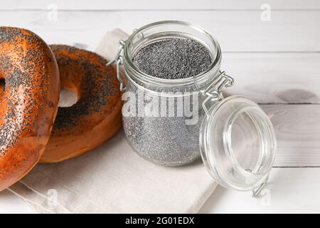 Vasetto con semi di papavero e gustosi bagel su legno chiaro sfondo Foto Stock