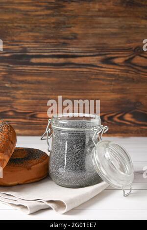 Vasetto con semi di papavero e gustosi bagel su legno chiaro sfondo Foto Stock