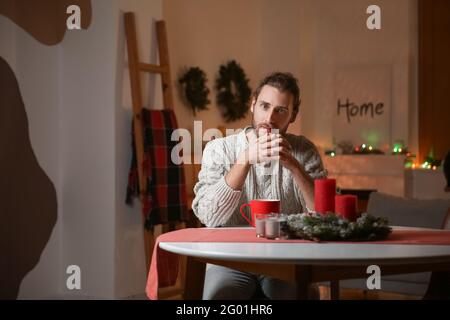 Bell'uomo seduto al tavolo in camera decorata per Natale Foto Stock