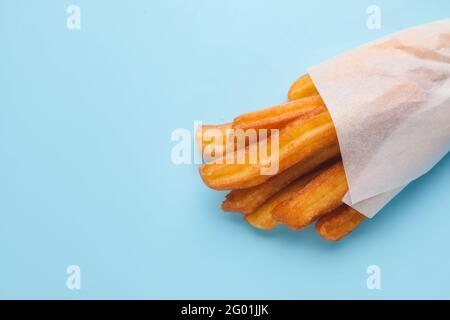 Gustosi churros in pergamena su sfondo a colori Foto Stock