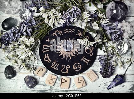 Ancora vita con cerchio zodiaco, rune, cristallo e fiori sul tavolo dell'altare delle streghe. Sfondo esoterico, gotico e occulto, mistico di Halloween e co di wicca Foto Stock