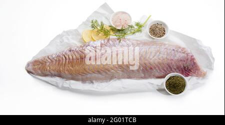 Da sopra di filetto di pesce di pollock crudo su carta con spezie ed erbe preparate per cucinare su fondo bianco Foto Stock