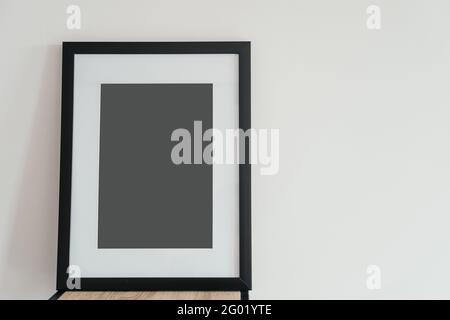 La cornice fotografica in legno bianco si trova all'interno su uno sfondo bianco. Cornice poster mockup. Foto Stock