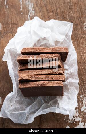 Pezzi di cioccolato con latte su fondo rustico di legno Foto Stock