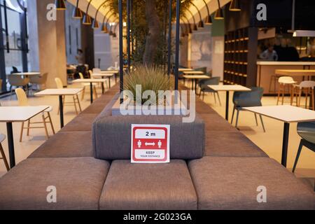 Immagine di sfondo dell'interno vuoto della corte del cibo al centro commerciale con segno sociale rosso di distanza, spazio di copia Foto Stock