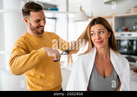 L'uomo fa un taglio di capelli alla donna a casa durante la quarantena. Foto Stock